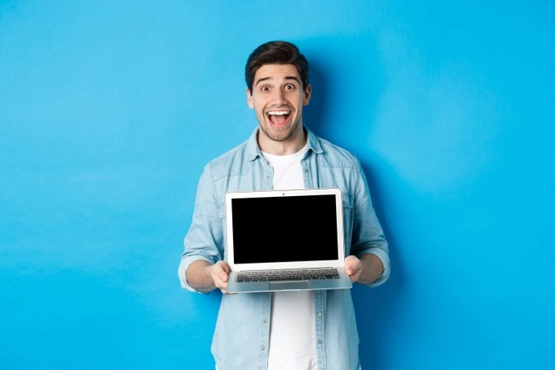 cheerful-smiling-man-making-presentation-showing-laptop-screen-looking-happy-standing-blue-background_1258-65256